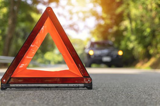 Red triangle, red emergency stop sign, red emergency symbol and black car stop and park on road.