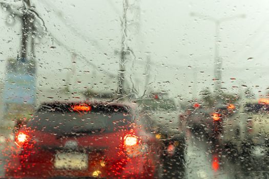 drive a car on the road stop witn trafic light with raindrop over the wind shield. Shot form wind shield