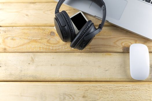 Top view headphone, laptop, Mouse and music player portable on wood table. With copy space for text or design.