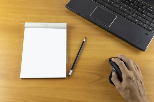 Top view office desk with hand hold mouse, laptop, keyboard, bill book and pencil on wood table . With copy space for text or design.