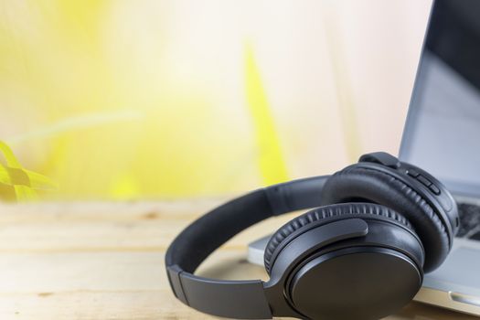 Wriless headphones and laptop on wood table in garden. With copy space for text or design. Technology concept.