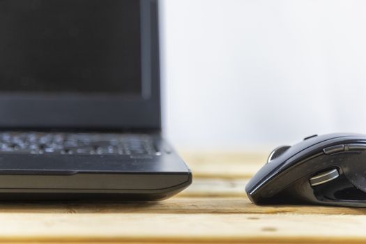 Office concept. Close up mouse and laptop on wood table. With copy space for text or design.