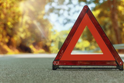 Autumn road red triangle, red emergency stop sign, red emergency symbol and black car stop and park on road.