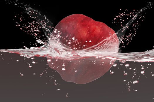 Red apple falling in to water with splash isolate on black background.