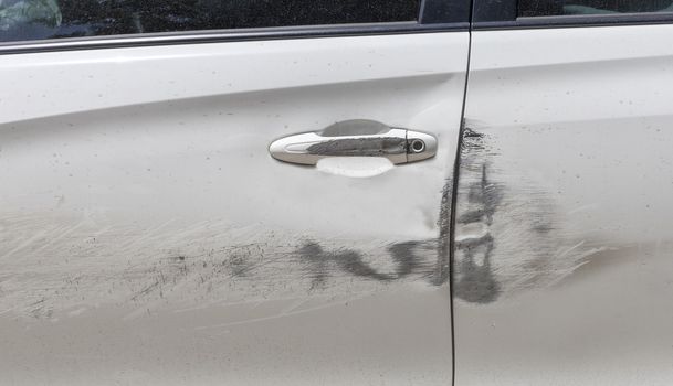 Car door handle and white car door have scratches from damaged by accident