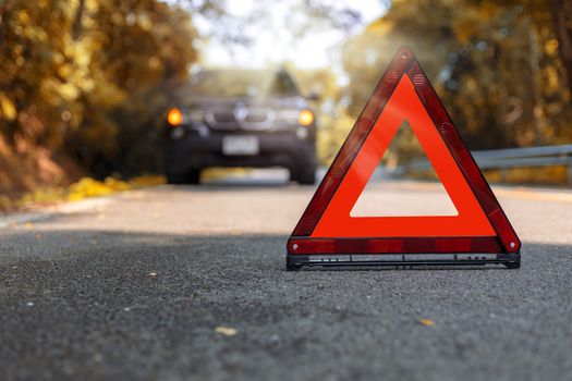 Red triangle, red emergency stop sign, red emergency symbol and black car stop and park on road.