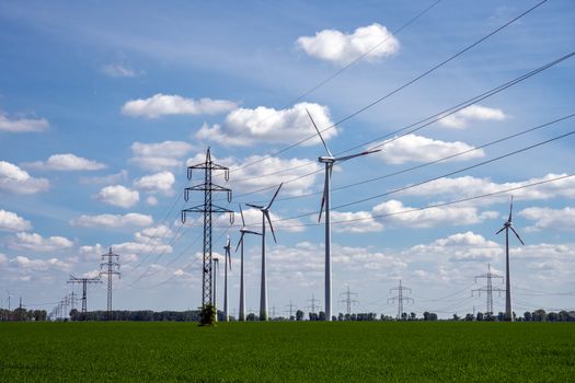 Overhead power lines and wind turbines in a cornfield seen in Germany