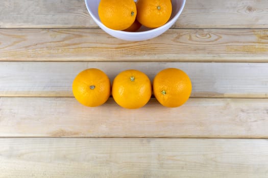 Top view Fresh oranges in white bowl on wood table. With copy space for text or design.