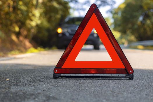 Red triangle, red emergency stop sign, red emergency symbol and black car stop and park on road.