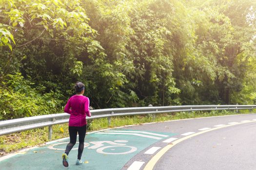 Women with pink long sleeve runing on road in morning time.