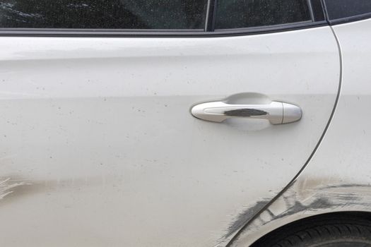 Car door handle and white car door have scratches from damaged by accident