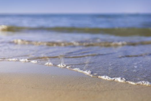 Soft wave from sea come to wet sand beach with blur clear sky background. With copy space for text or design
