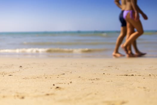 Summer Holiday concept. Clear sand with blur guy, sea and clear sky background. Soft focus and focus selective sand.