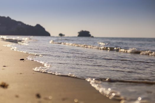 Soft wave from sea come to wet sand beach with blur clear sky background. With copy space for text or design
