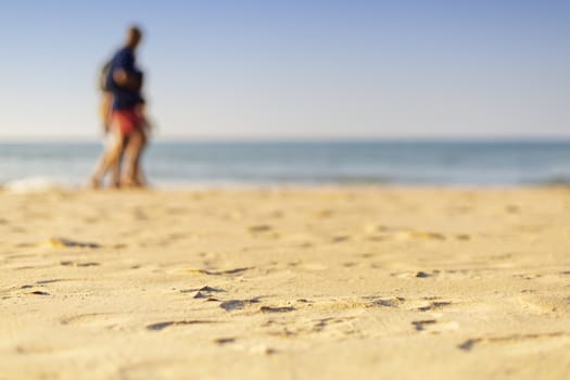 Holiday concept. Clear sand with blur guy, sea and clear sky background. Soft focus and focus selective sand.