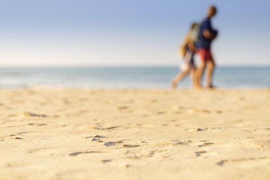 Holiday concept. Clear sand with blur guy, sea and clear sky background. Soft focus and focus selective sand.