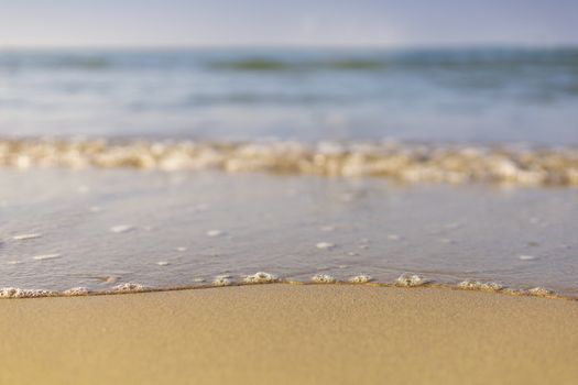 Soft wave from sea come to wet sand beach with blur clear sky background. With copy space for text or design