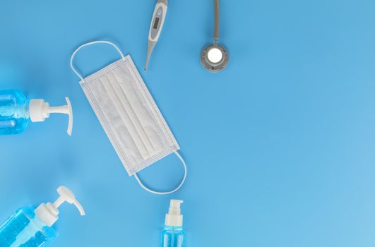 Top view Hygienic masks digital thermometer, Stethoscope , alcohol spray on blue background. Medical face mask, alcohol sanitizer, thermometer on blue background with copy space.