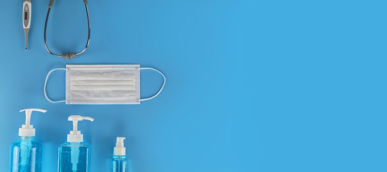 Top view Hygienic masks digital thermometer, Stethoscope , alcohol spray on blue background. Medical face mask, alcohol sanitizer, thermometer on blue background with copy space.