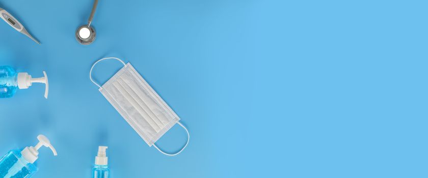 Top view Hygienic masks digital thermometer, Stethoscope , alcohol spray on blue background. Medical face mask, alcohol sanitizer, thermometer on blue background with copy space.