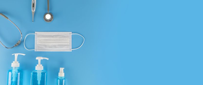 Top view Hygienic masks digital thermometer, Stethoscope , alcohol spray on blue background. Medical face mask, alcohol sanitizer, thermometer on blue background with copy space.