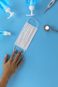 Top view  Human hand, Hygienic masks digital thermometer, Stethoscope , alcohol spray on blue background. Hand man, Medical face mask, alcohol sanitizer, thermometer on blue background with copy space.