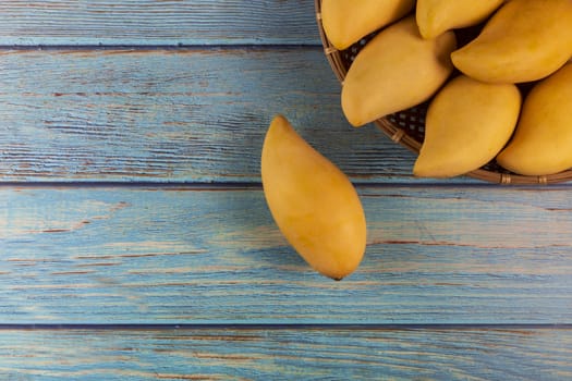 Yellow Fresh mangos 0n blue wood table. Mango tropical fruit on wood background. mangos with copy space for text or design. summer concept. 