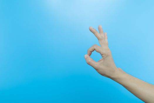 Women hand show gesturing  sign on light blue background. human hand make OK sign on blue background with copy space.