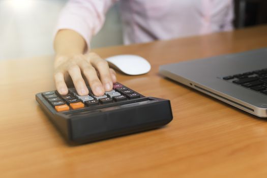 Women hand using calculator on office desk. Female hand press calculator. Business woman hand using calculator at office. Family budget calculation on wood table.