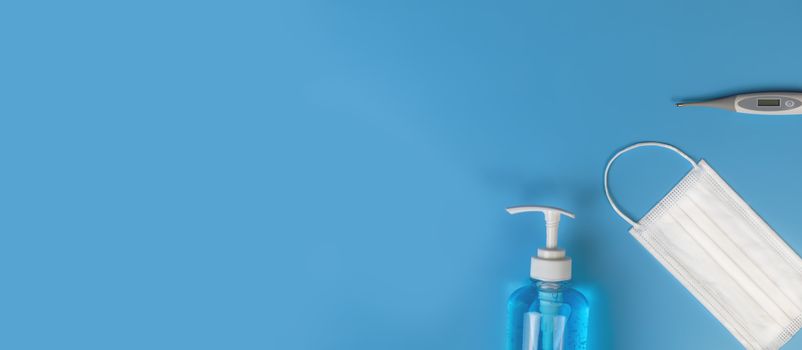 Top view Hygienic masks digital thermometer , alcohol spray on blue background. Medical face mask, alcohol sanitizer, thermometer on blue background with copy space.
