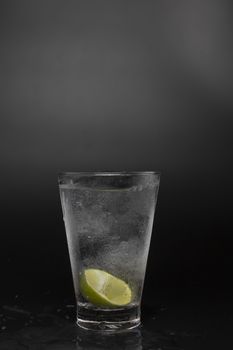 Soad water in glass with lime on black background. cool soda water and lime with copy space.