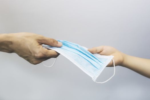 Women hand give to surgical mask. Women hand give to medical face mask with child hand for protect virus. With copy space. Mother hand give to surgical mask with daughter hand.
