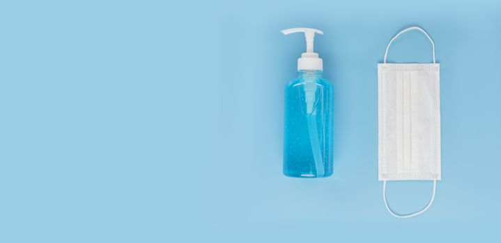 Top view medical face mask and alcohol gel on light blue background with copy space. Face mask and hand sanitizer gel in pump head bottle.