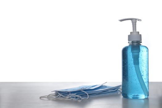 Face mask with alcohol sanitizer gel hand wash on wood table and white background with copyspace for text or design.