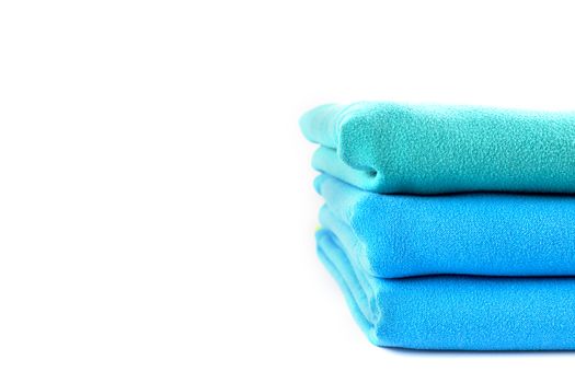 Close up half stack towels green and blue on white background with copy space.
