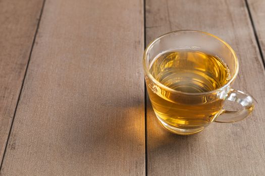 Close up hot tea cup on wood table . hot tea in handle glass with copy space for text or design.