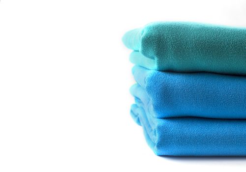 Close up half stack towels green and blue on white background with copy space.