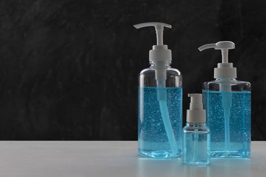 Blue alcohols gel on white table and  calcium oxide background. Hand sanitizer gel for clean. Hand sanitizer in 3 different size dump bottle. 
