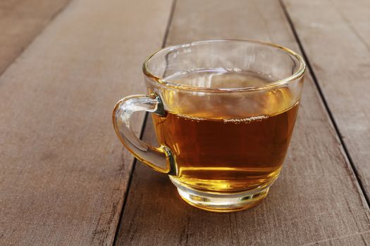 Close up hot tea cup on wood table . hot tea in handle glass with copy space for text or design.