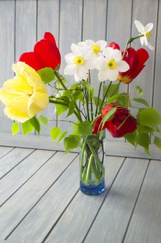 Spring bouquet with red and yellow tulips and narcissus. Fresh flowers. Colorful bouquet of fresh spring flowers on blue wooden background.