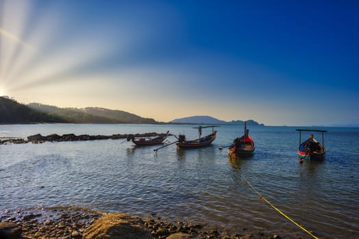 Small wooden fisherman boads on water sea witn sun ray and clear sky. With copy space for text or design.