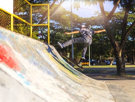 Young boy jump on ramp with skateboard outdoor.