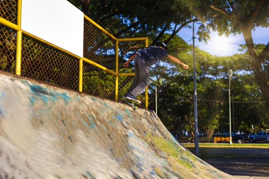 Young boy jump on ramp with skateboard outdoor.