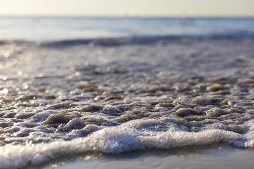 Soft wave from sea come to wet sand beach with blur clear sky background. With copy space for text or design