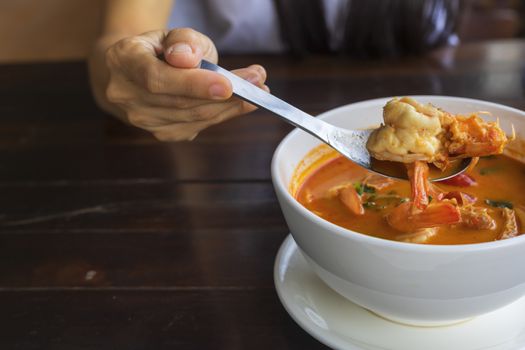Close up Woman hand hold a spoon with shrimp from Tom Yum Kung,  With copy space for text or design.