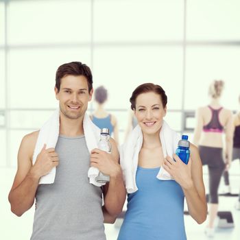 Composite image of portrait of a happy fit couple with water bottles