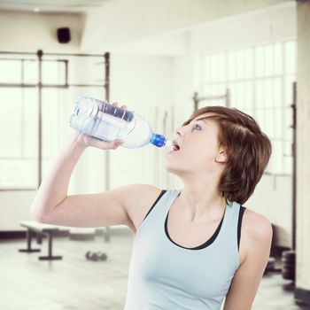 Pretty brunette drinking water against interior of a gym