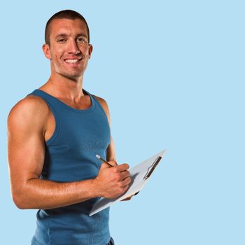Portrait of confident sports coach writing on clipboard against blue background