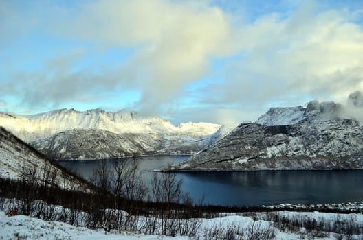 The bay with crystal water lying between snowy mountains