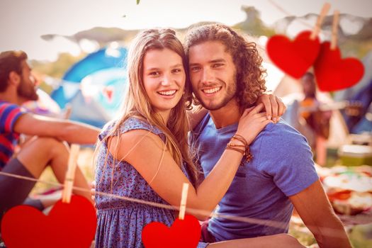 Hipster couple smiling at camera against hearts hanging on a line
